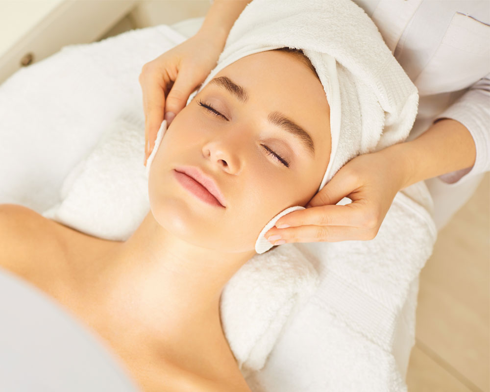 Esthetician performing a facial cleansing on a client